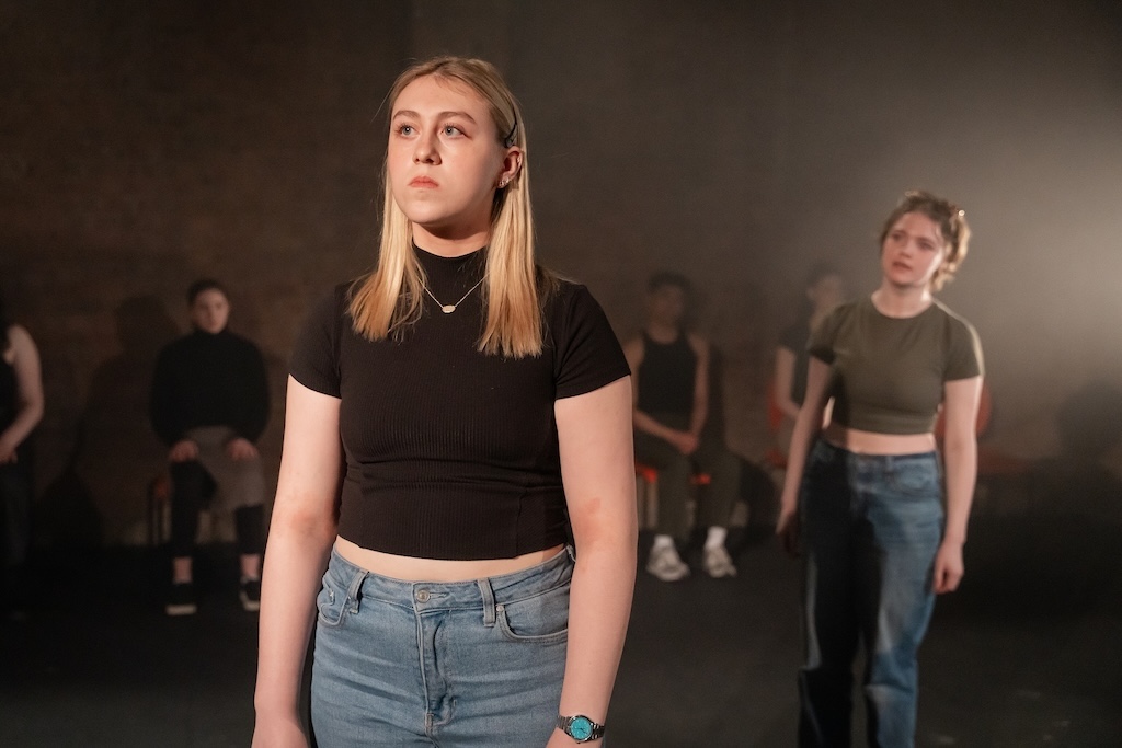 Action shot of the spring 2024 Shakespeare in Performance at RADA final presentation of Julius Caesar. An actor stands in mid-performance as a second actor, behind her, steps forward.